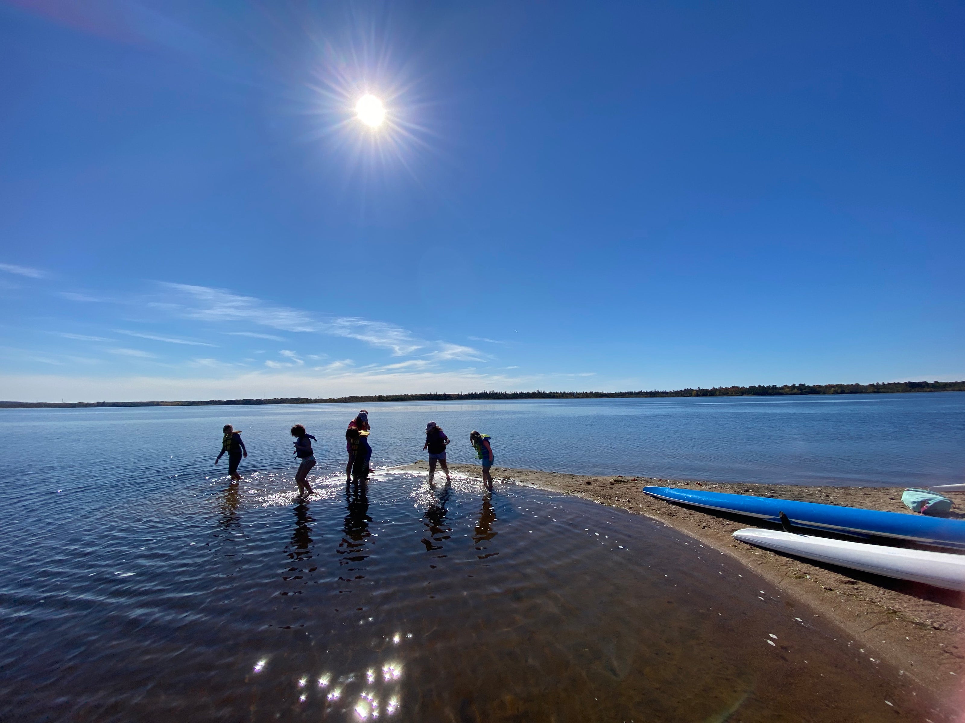 Young paddlers standing on the beach of Aylmer Island on a stunning day at the ORCC.