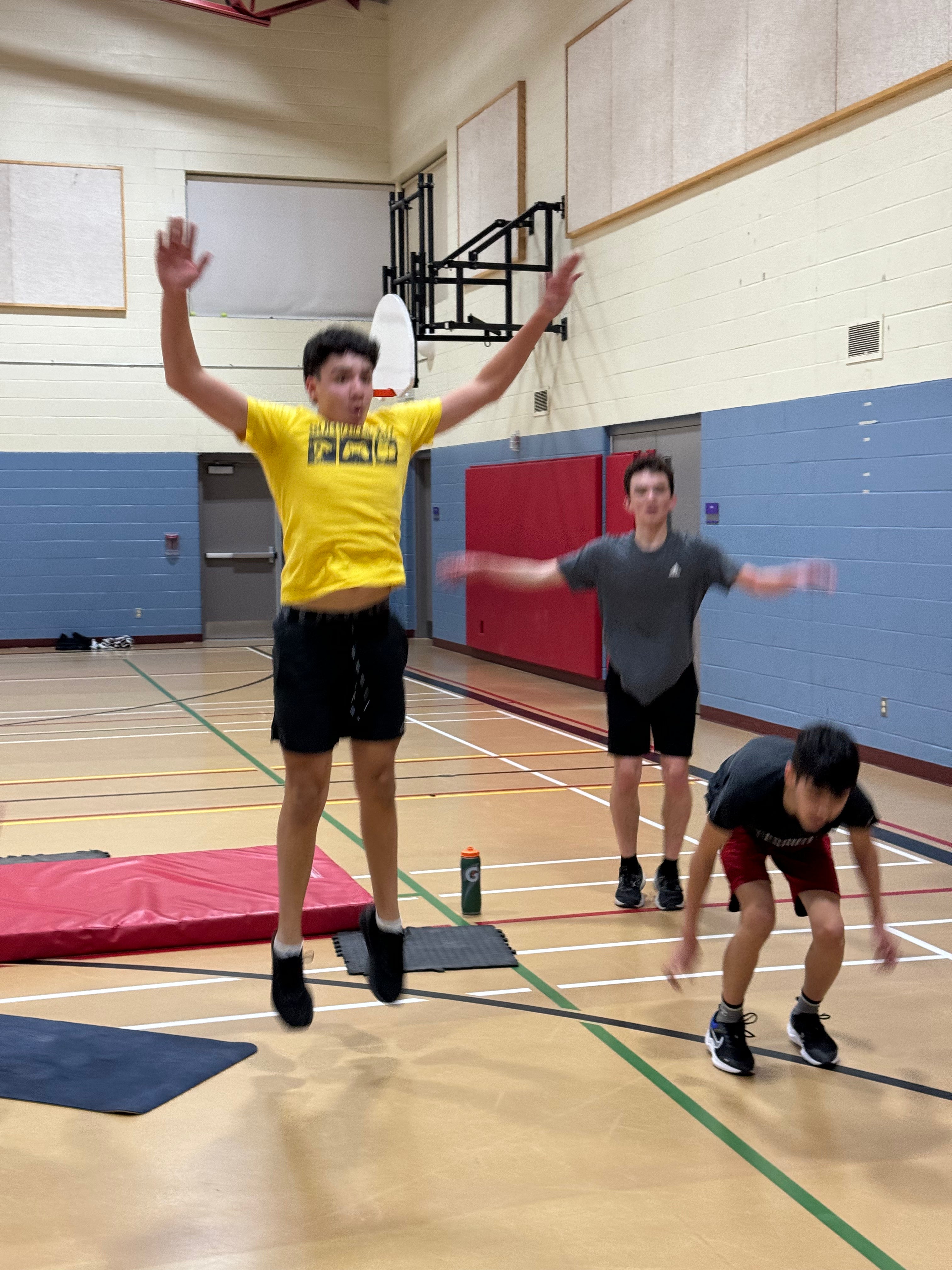 Athletes completing some star jumps while in a school gym.