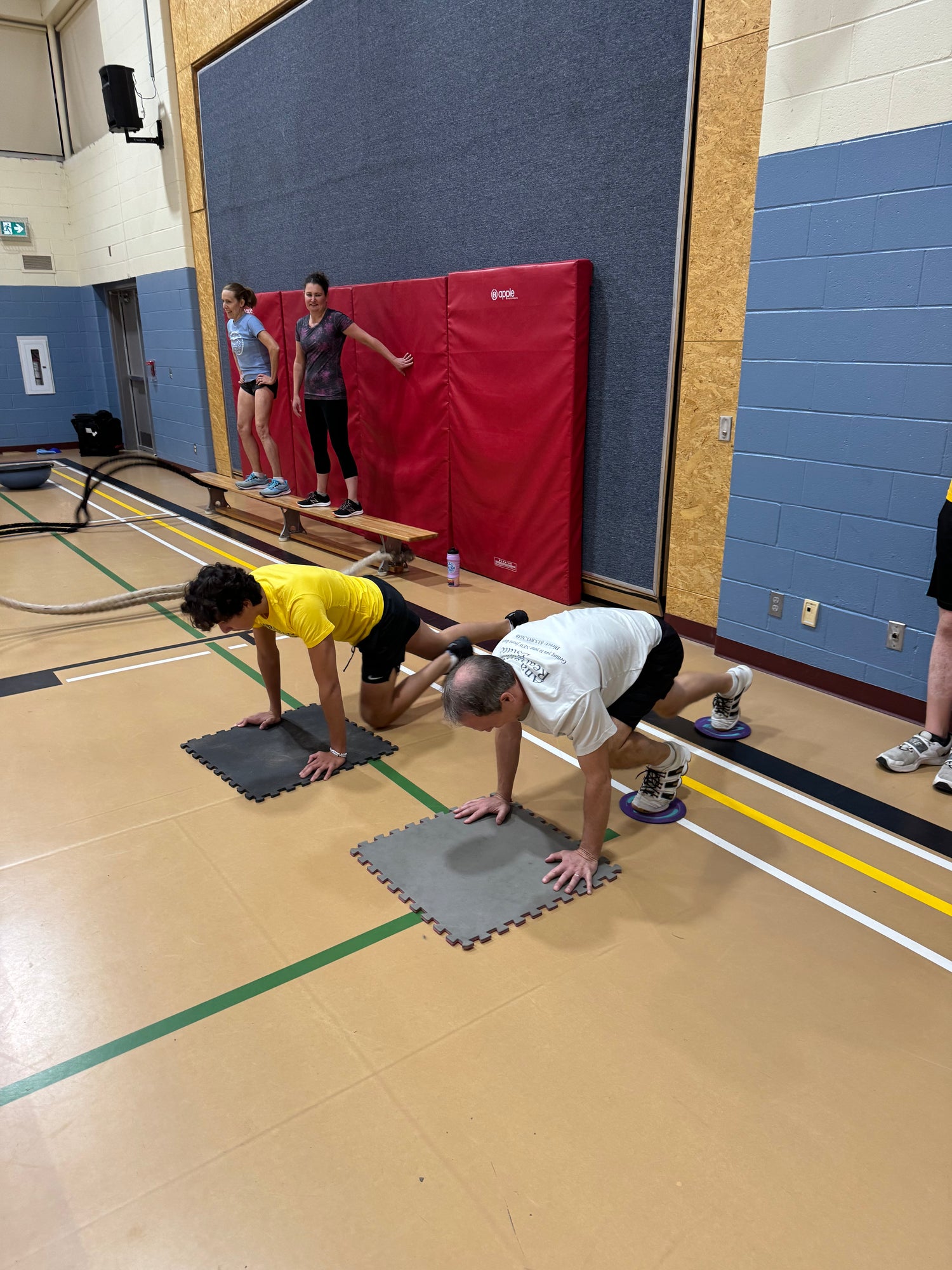 Athletes do mountain climber exercise in a school gym as part of winter training.